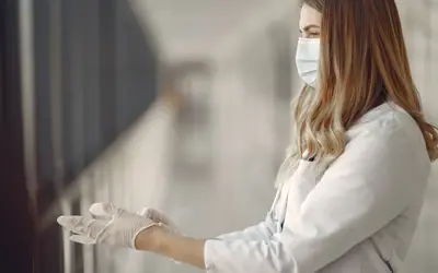 Woman in a mask and uniform puts on gloves